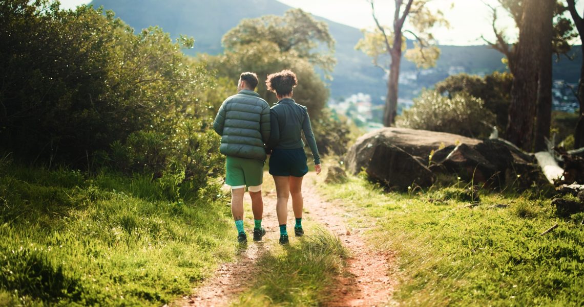 Couple walking together along a sunlit forest trail