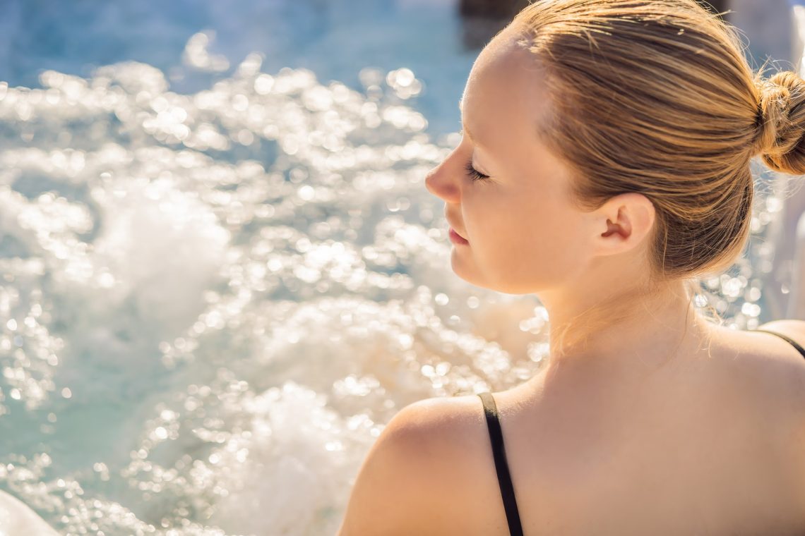 Woman relaxing in an outdoor hot tub with mountain views