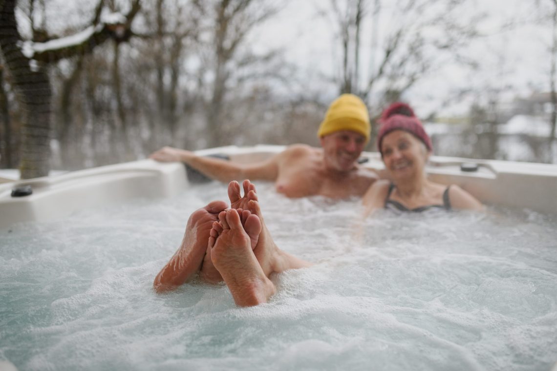 Close-up of a couple relaxing their feet in a hot tub during winter